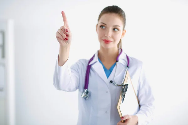 Woman doctor standing with folder at hospital and pointing up — Stock Photo, Image