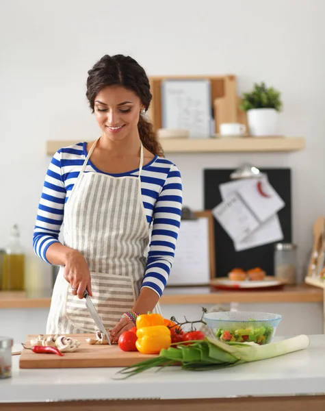 Jonge vrouw snijden groenten in de keuken — Stockfoto