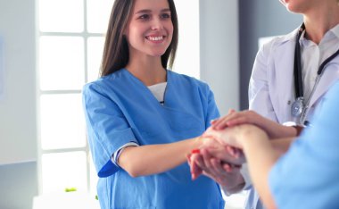 Doktorlar ve hemşireler tıbbi bir ekipte el ele tutuşuyorlar.