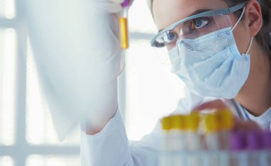 Hastanedeki kan örneğini analiz eden güzel bir kadın laboratuvar asistanı portresi.