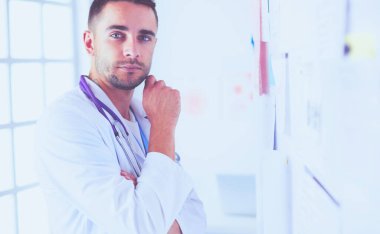 Genç ve kendinden emin erkek doktor portresi tıp ofisinde duruyor..