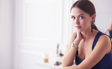 Beyaz arka planda izole edilmiş bir sandalyede oturan genç kadın.