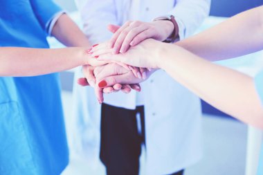 Doktorlar ve hemşireler tıbbi bir ekipte el ele tutuşuyorlar.