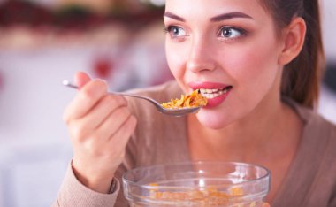 Gülümseyen çekici kadın mutfağın içinde kahvaltı yapıyor.