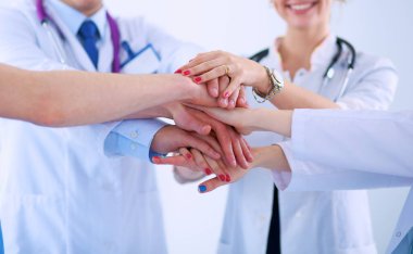 Doktorlar ve hemşireler tıbbi bir ekipte el ele tutuşuyorlar.