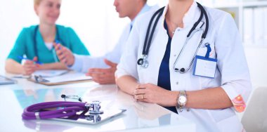 Masada oturan gülümseyen güzel genç bayan doktor.