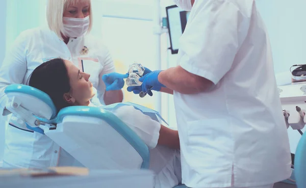 Dentista masculino senior en consultorio dental hablando con paciente femenino y preparándose para el tratamiento — Foto de Stock