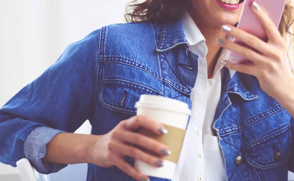喫茶店でコーヒーを飲みながら携帯電話で話す若い女性 — ストック写真