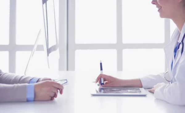 Portrait of middle aged female doctor using digital tablet while sitting at exam room and working — Stock Photo, Image