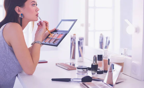 Brunette woman applying make up for a evening date in front of a mirror — Stock Photo, Image