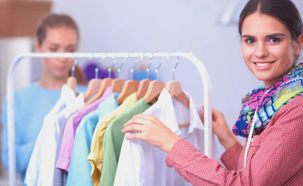 Beautiful young stylist near rack with hangers — Stock Photo, Image