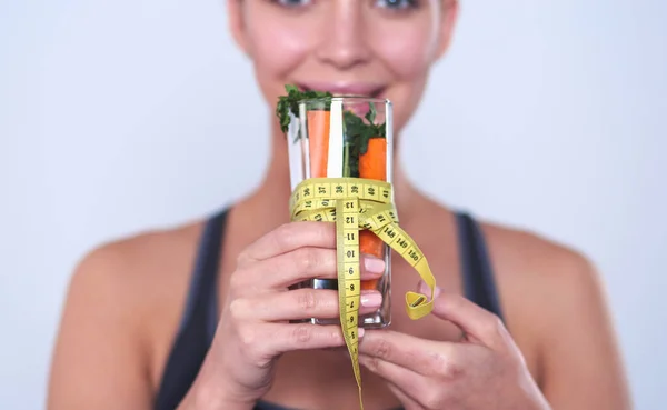 Femme tenant verre à boire plein de salade de fruits frais avec un ruban à mesurer autour du verre — Photo