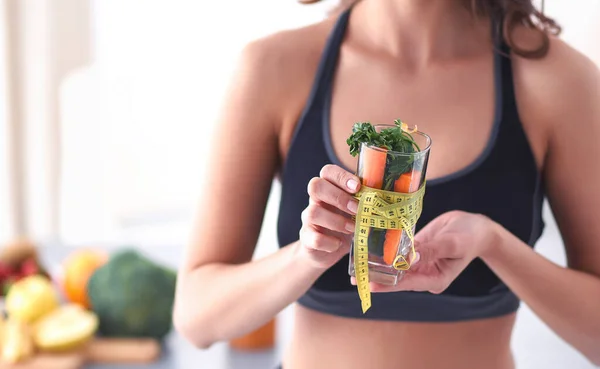 Mulher segurando um copo cheio de salada de frutas frescas com uma fita métrica ao redor do copo — Fotografia de Stock