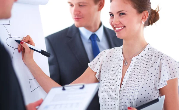 Businesswoman writing on flipchart while giving presentation to colleagues in office — Stock Photo, Image