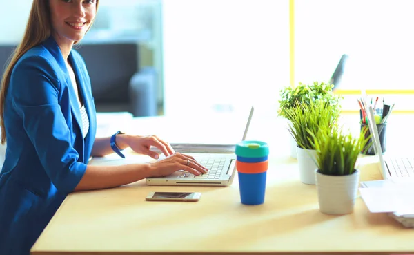 Femme assise sur le bureau avec ordinateur portable — Photo