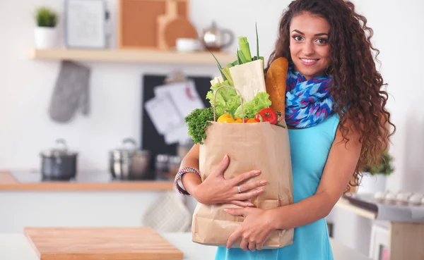 Junge Frau hält Einkaufstüte mit Gemüse in der Küche. — Stockfoto