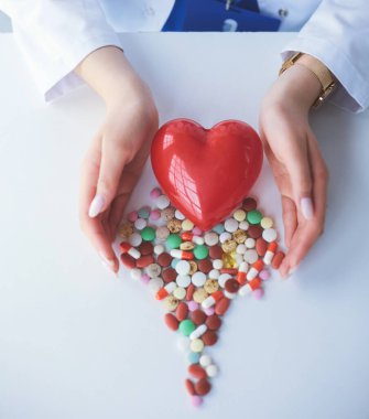 Masada kırmızı kalbi ve steteskopu olan kardiyolog.