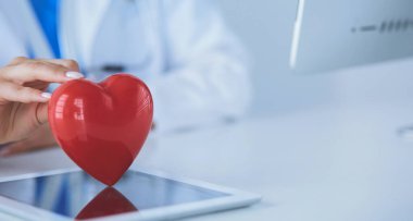 Steteskop tutan, kalbi hafif arka planda olan kadın bir doktor.