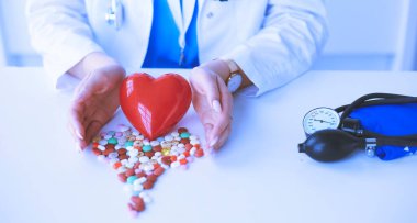 Masada kırmızı kalbi ve steteskopu olan kardiyolog.