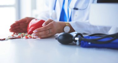 Masada kırmızı kalbi ve steteskopu olan kardiyolog.