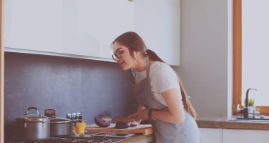 Mutfakta yemek yapmak için tablet bilgisayar kullanan genç bir kadın.