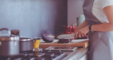 Yeni mutfakta yemek pişiren kadın sebzelerle sağlıklı yemekler yapıyor.