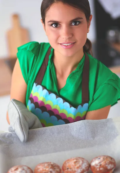 Glimlachende jonge vrouw in de keuken, geïsoleerd op de achtergrond — Stockfoto