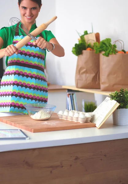 Smiling young woman in the kitchen, isolated on background — Stock Photo, Image