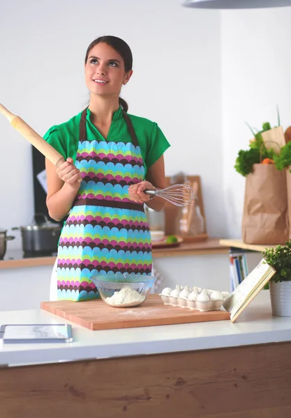 Leende ung kvinna i köket, isolerad på bakgrunden — Stockfoto