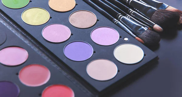 Makeup brushes and make-up eye shadows on desk — Stock Photo, Image