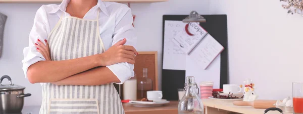 Glimlachende jonge vrouw in de keuken, geïsoleerd op kerst achtergrond — Stockfoto