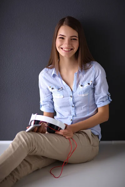 Chica sonriente con auriculares sentados en el suelo —  Fotos de Stock