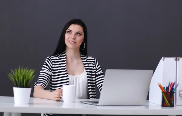 Jonge vrouw met een laptop zitten geïsoleerd op grijze achtergrond — Stockfoto