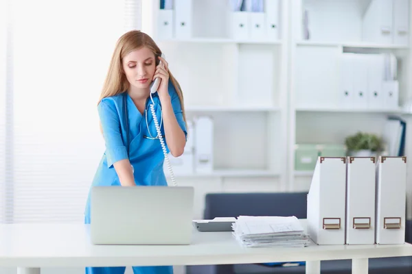 Medical doctor woman with computer and telephone. — Stock Photo, Image