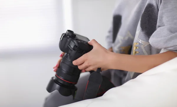 Woman sitting on a sofa in her house with camera — Stock Photo, Image