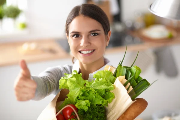 Mujer joven sosteniendo bolsa de la compra de comestibles con verduras y mostrando ok — Foto de Stock