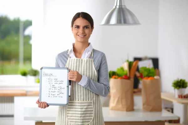 Donna in cucina a casa, in piedi vicino alla scrivania con cartella — Foto Stock