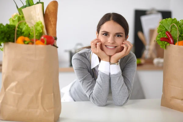 Retrato de una mujer sonriente cocinando en su cocina sentada —  Fotos de Stock