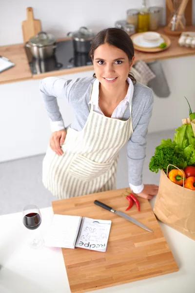 Nainen tekee terveellistä ruokaa seisoo hymyillen keittiössä — kuvapankkivalokuva