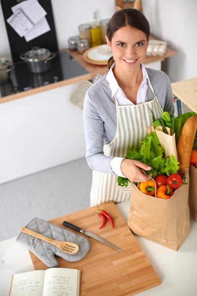 Woman with shopping bags in the kitchen at home, standing near desk — Stock Photo, Image