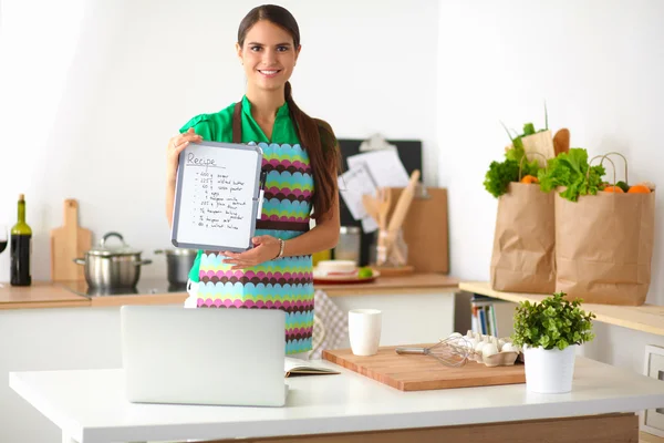 Leende ung kvinna i köket, isolerad på bakgrunden — Stockfoto