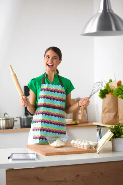 Улыбающаяся молодая женщина на кухне, изолированная на заднем плане — стоковое фото