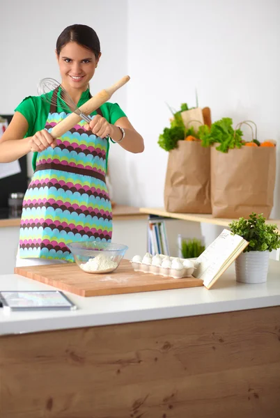 Leende ung kvinna i köket, isolerad på bakgrunden — Stockfoto