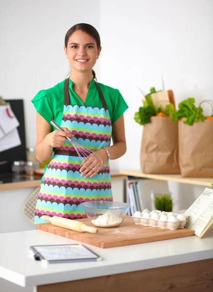 Sorridente giovane donna in cucina, isolata sullo sfondo — Foto Stock