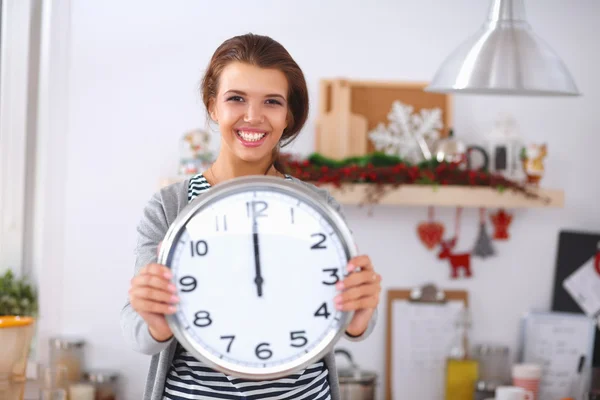 Happy young woman showing clock in christmas decorated kitchen — Stock Photo, Image