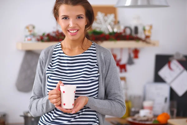 Portrait de jeune femme avec tasse sur fond intérieur de cuisine. — Photo