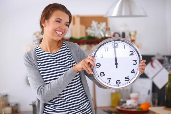 Happy young woman showing clock in christmas decorated kitchen — Stock Photo, Image