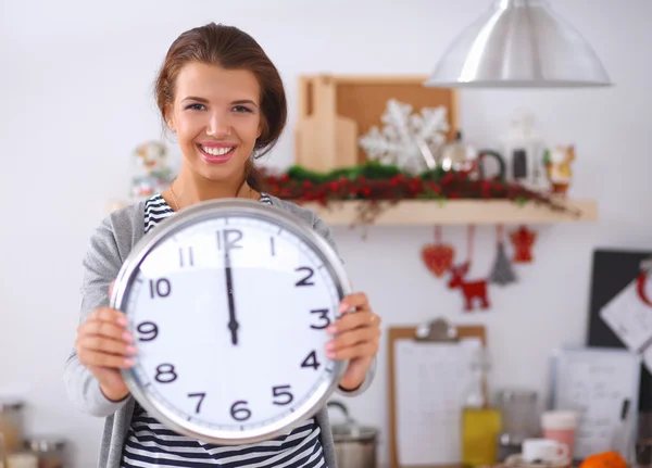 Gelukkig jong vrouw tonen klok in kerst versierd keuken — Stockfoto