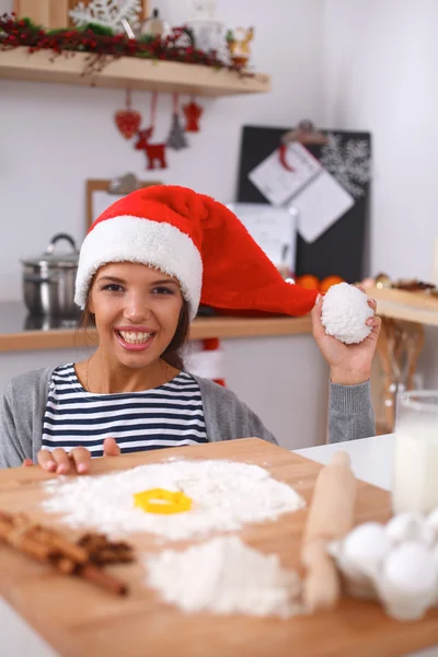 幸せな若い女性笑顔幸せを持って楽しみますクリスマスの準備を身に着けているサンタの帽子 — ストック写真