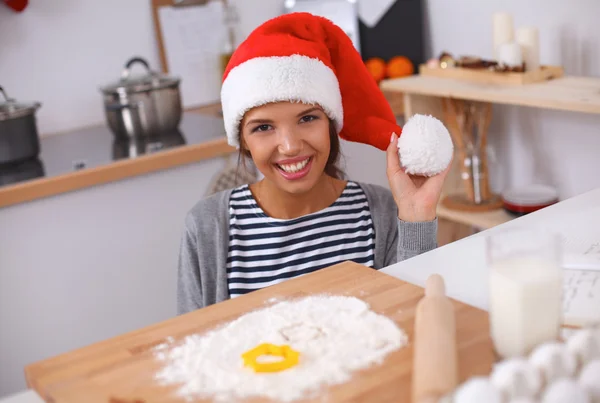 Lykkelig ung kvinde smilende glad for at have det sjovt med juleforberedelser iført Santa hat - Stock-foto